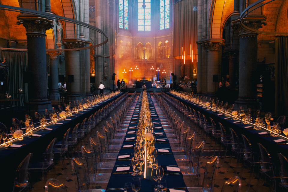 Lange dinertafels met lichtlijnen in de Gratiekerk voor het jubileumevent van Grundfos Belgium.