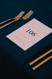 Tafelkaart met nummer 106 op een donkerblauw gedekte tafel voor het Grundfos-jubileum.
