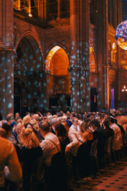 Gasten dineren in de Gratiekerk met lichtprojecties en een zwevende wereldbol.