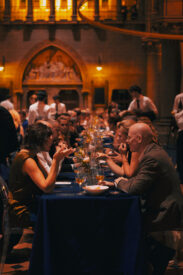 Gasten dineren aan lange tafels in de Gratiekerk tijdens de Grundfos 50 Years Celebration.