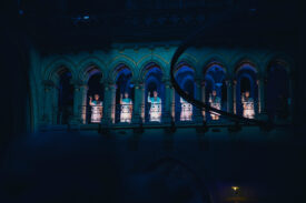 Performers in witte kostuums verlichten de galerij van de Gratiekerk tijdens de dinershow.